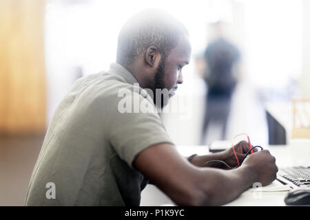 Uomo seduto alla scrivania che controlla un dispositivo con misuratori di flusso Foto Stock