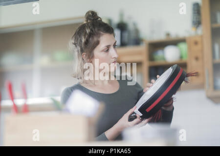 Donna in piedi in cucina che fissa un manipolatore robotico aspirapolvere Foto Stock