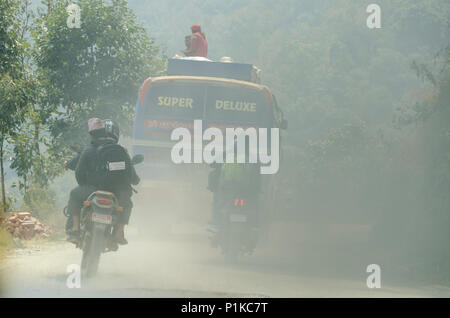 Motocicli tentativo di sorpasso sul bus polverosa strada di montagna Trishuli autostrada, Kathmandu, Nepal Foto Stock