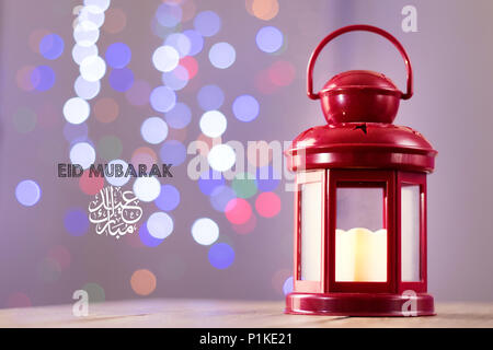 Eid al-Fitr Mubarak saluto tipografia con sfondo bokeh di fondo. Lanterna arabo su sfondo di legno Foto Stock