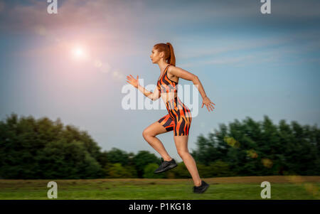 Donna che indossa Abbigliamento colorato in esecuzione in un parco Foto Stock