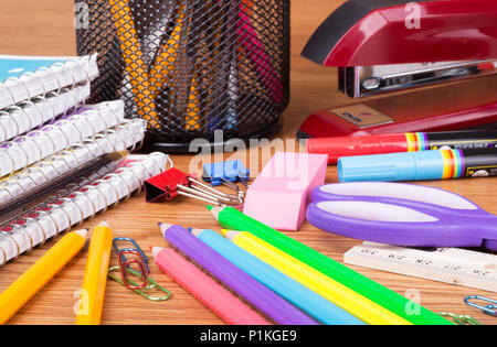 Primo piano di un assortimento di scuola e di forniture per ufficio su una superficie in legno Foto Stock