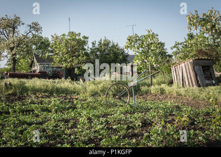 In casa coltivatore a mano da una vecchia bicicletta. Attrezzi da giardino. Foto Stock