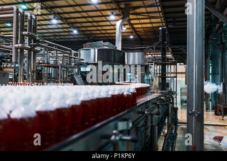 Bottiglie di soda rosso nella linea di fabbrica. Foto Stock