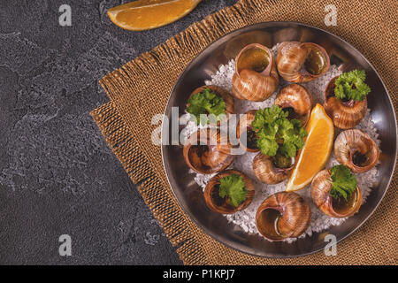 Lumache fritte con limone, baguette e prezzemolo, vista dall'alto. Foto Stock