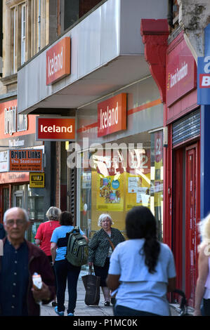 Le persone e gli amanti dello shopping a piedi passato indipendenti e negozi di beneficenza ed un ramo di Islanda, situato sulla Finchley Road High Street a Londra del nord. Foto Stock