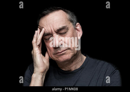 Primo piano alto contrasto Ritratto di sottolineato uomo infelice con mano a faccia su sfondo nero Foto Stock