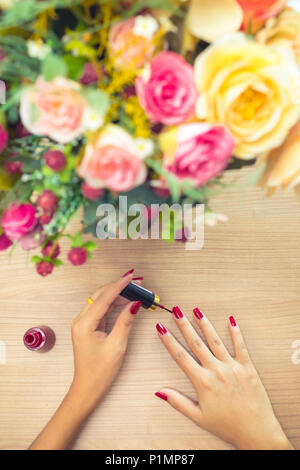 Donna colore rosso applicazione polacco sulle unghie. Relax , la cura e il concetto di bellezza Foto Stock