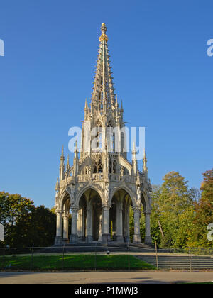 Persone relax su un prato con alberi di fronte al monumento a Re Leopoldo I in stile neo-gotico nel parco di Laeken, Bruxelles, Foto Stock