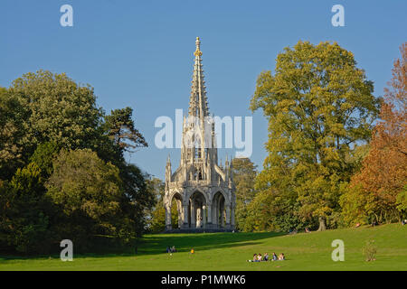 Persone relax su un prato con alberi e il Monumento a Re Leopoldo I in stile neo-gotico nel parco di Laeken a Bruxelles in un pigro e soleggiata domenica dopo Foto Stock