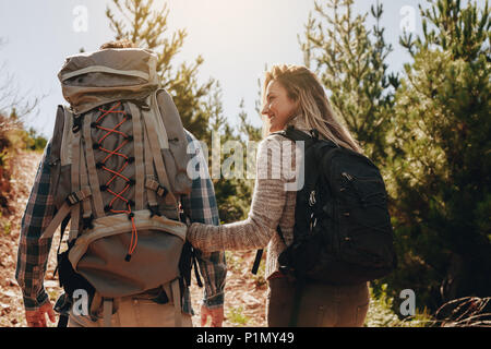 Vista posteriore della coppia di giovani escursionismo. Giovane uomo e donna con i loro zaini trekking in montagna. Foto Stock