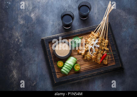 Pollo saté o Sate Ayam - Malaysian famoso cibo. È un piatto di agguerriti, infilzato e carne alla brace, servita con una salsa di arachidi. Darkphoto. Vista superiore Foto Stock