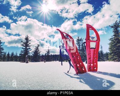 Set di rosso le racchette da neve. Racchette da neve e uno zaino stand sulla neve in montagna. Soleggiata giornata invernale. Foto Stock