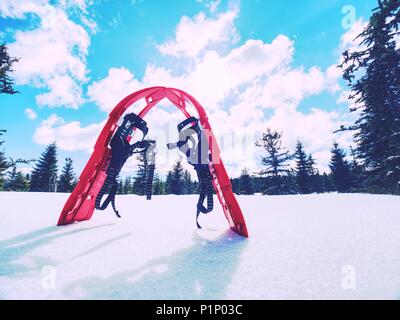 Set di rosso le racchette da neve. Racchette da neve e uno zaino stand sulla neve in montagna. Soleggiata giornata invernale. Foto Stock