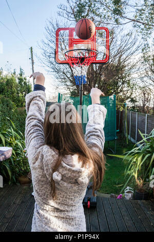 Persona ragazza, la ripresa di un cestello, giocare a basket in giardino, sfera in transito, palla in aria, basket ball, Dublino Irlanda Foto Stock