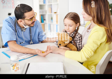 Pediatra offrendo vitamine per bambino Foto Stock