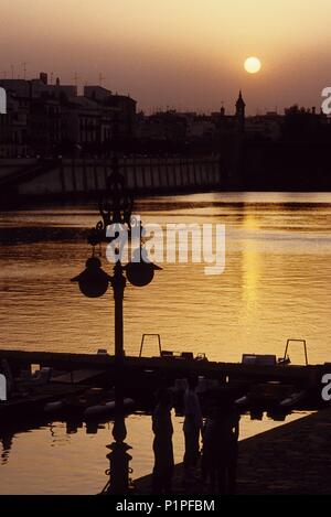 Il fiume Guadalquivir shore con una vista al Barrio (quarto) de Triana al tramonto. Foto Stock