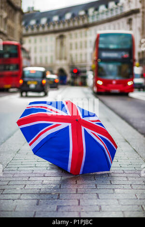 Londra, Inghilterra - British ombrello occupato a Regent Street con iconica red double-decker bus e taxi neri in movimento Foto Stock