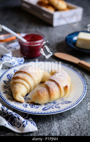 Tradizionali croissant appena sfornati serviti con confettura di lamponi e burro Foto Stock
