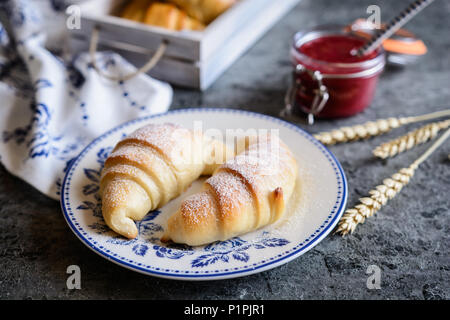 Tradizionali croissant appena sfornati serviti con confettura di lamponi e burro Foto Stock