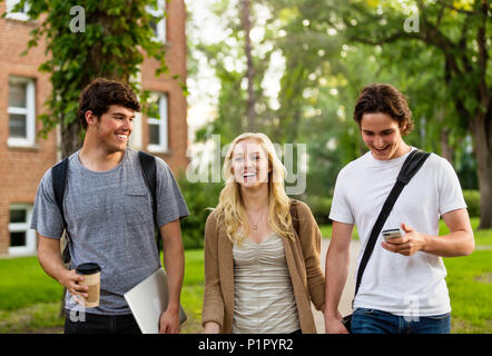 Tre amici camminare e parlare al campus universitario; Edmonton, Alberta, Canada Foto Stock