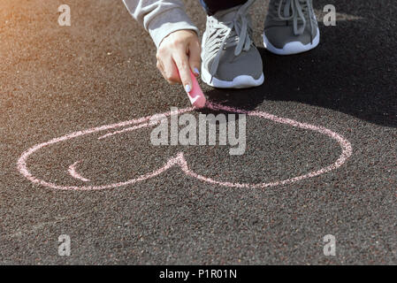 Bambino la mano attrae i cuori, disegni chalk su asfalto Foto Stock