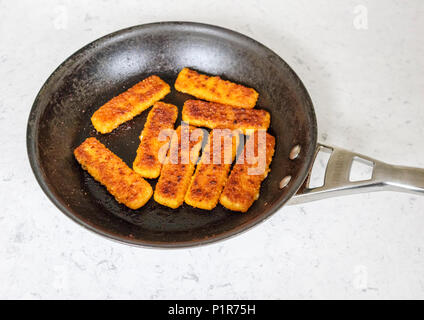 Pentola piena di sfrigolanti feshly cotte golden brown le dita di pesce Foto Stock