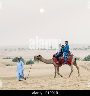 Una famiglia su un cammello safari sulle dune Lakhmana; Damodara, Rajasthan, India Foto Stock