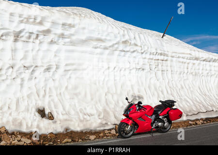 Vista da la Beartooth Highway di un motociclo parcheggiato lungo un cumulo di neve sul ciglio della strada; Cody, Wyoming, Stati Uniti d'America Foto Stock