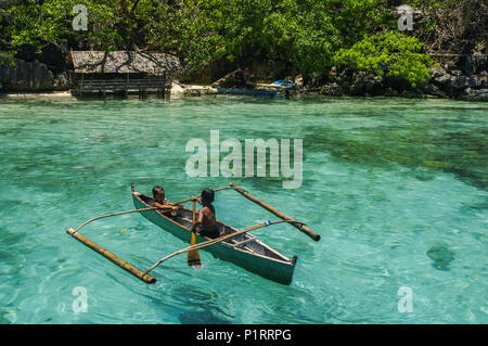 Ragazzi paddling in una canoa, pesca in acque turchesi dell'Oceano Indiano; Isole Andamane, India Foto Stock