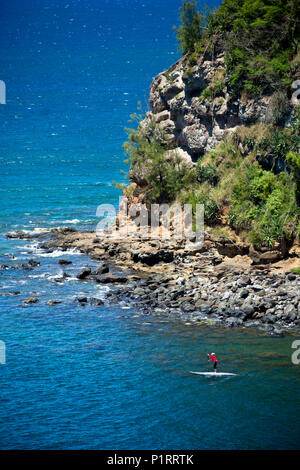 Donna paddling fuori da Maliko Gulch in stand up paddle board, vicino para; Maui, Hawaii, Stati Uniti d'America Foto Stock