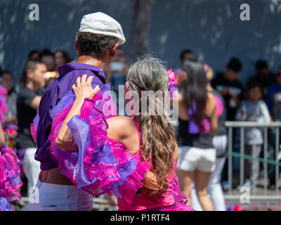 Un uomo e una donna di ballo salsa nel mezzo di una sfilata con una folla cercando su Foto Stock