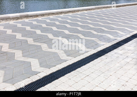 Monotono di mattoni grigi di pavimentazione di pietra a riverbank. vista prospettica Foto Stock