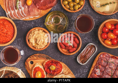 Tipiche tapas spagnole concetto. Concetto includono fette di prosciutto, il chorizo, salsiccia, bocce con olive, pomodori, acciughe, purea di ceci, formaggio. Foto Stock