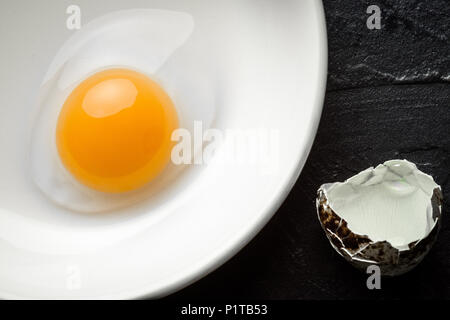 Materie rotto quaglia tuorlo d'uovo nella ciotola bianco Foto Stock