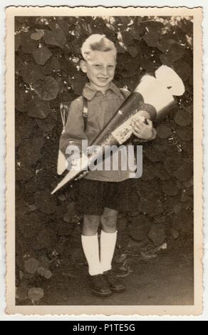 Germania- circa 1940s: Vintage foto mostra la pupilla ragazzo con 'Schultute' o a scuola di cono, dolci per il primo giorno di scuola. Studio foto con Tinta seppia. Foto Stock