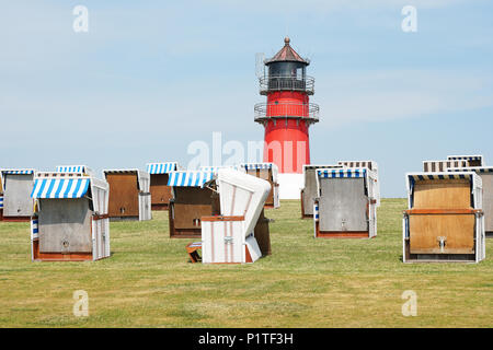 Diga o dyke con incappucciati sdraio in spiaggia e faro in Buesum, Germania Foto Stock