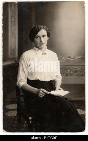 Germania - circa 1920s: Vintage mostra fotografica di una giovane donna. Indossa Edwardian acconciatura. Retrò in bianco e nero studio fotografico con effetto seppia. Foto Stock