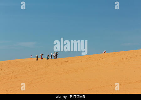 Mui Ne, Vietnam - Gennaio 2014: gruppo di turisti asiatici con ombrelloni nel paesaggio del deserto rosso / dune di sabbia di Mui Ne, Vietnam Foto Stock