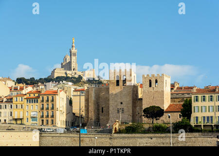 Vista dell'abbazia di Saint Victor al tramonto con le sue possenti torri quadrate, dominata dalla basilica di Notre Dame de la Garde sulla cima di T Foto Stock