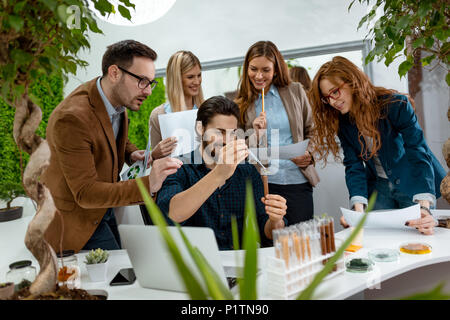 Team di biologi università analizzando il campione di piante in provetta, irrigazione con gocce di fluido nutriente. Foto Stock