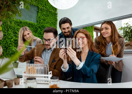 Team di biologi università analizzando il campione di piante in laboratorio, tubo di irrigazione con gocce di fluido nutriente. Foto Stock