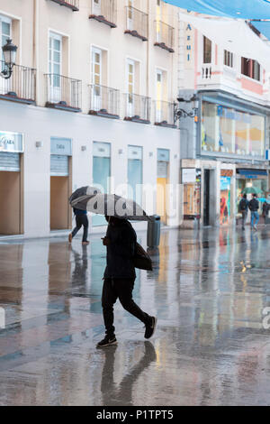 Madrid, Spagna: pedoni con ombrelloni a piedi lungo Calle de Preciados vicino a Puerta del Sol. Foto Stock