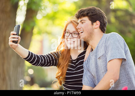 Un giovane uomo e giovane donna prendendo un autoritratto su uno smart phone; Edmonton, Alberta, Canada Foto Stock