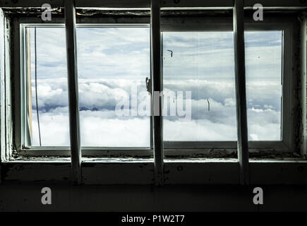 Decrepito vecchia finestra con una vista del mare di nubi Foto Stock