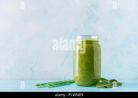 Di colore verde frullati / succo in un recipiente su uno sfondo blu. Foto Stock