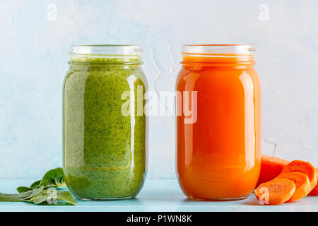 Arancione/verde frullati colorati / succo in un recipiente su uno sfondo blu. Foto Stock