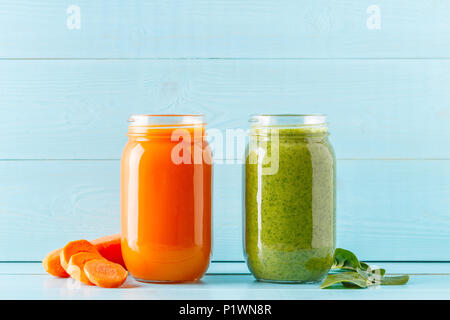 Arancione/verde frullati colorati / succo in un recipiente su uno sfondo blu. Foto Stock