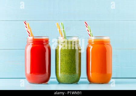 Arancione/verde/rosso frullati colorati / succo in un recipiente su uno sfondo blu. Foto Stock