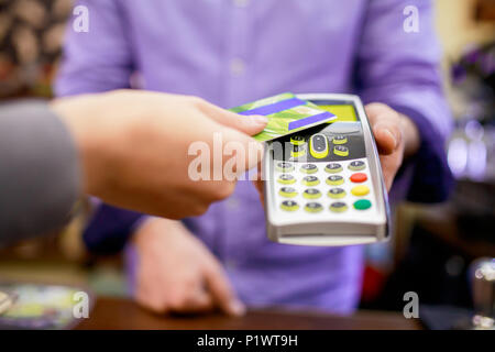 Immagine del compratore l uomo con la carta di credito e il venditore con il terminale in mano Foto Stock